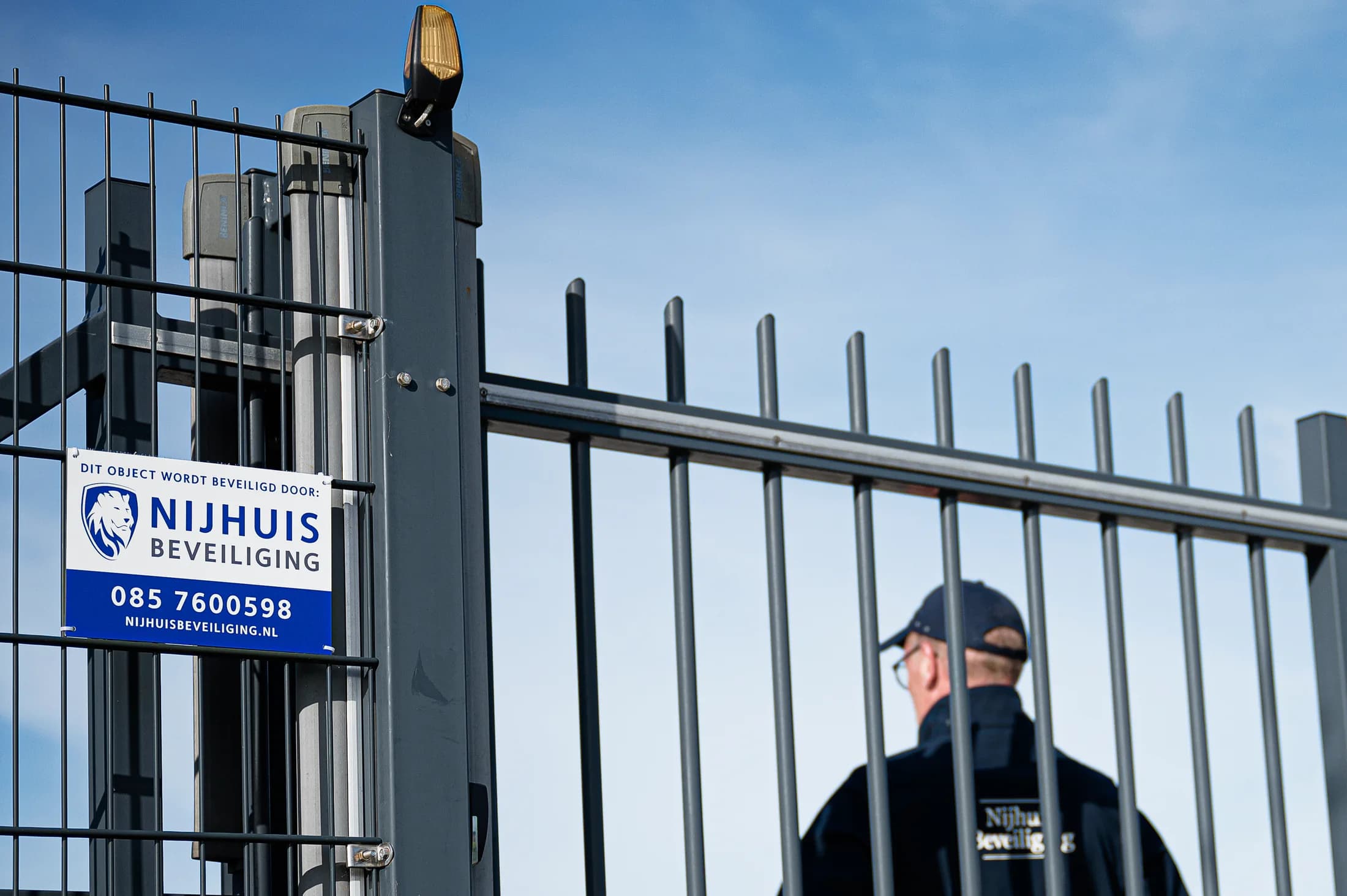 Beveiliger van Nijhuis Beveiliging bij het toegangshek van een bedrijfsterrein
